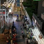 A lively urban night market scene with street food vendors and neon lights.