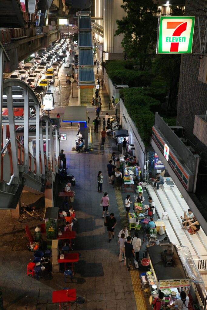 A lively urban night market scene with street food vendors and neon lights.