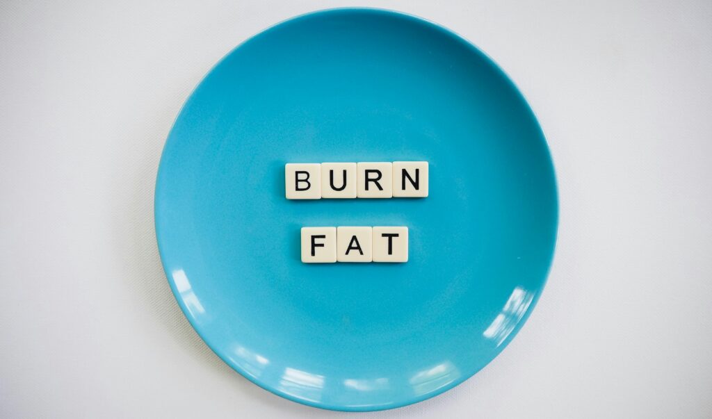 A conceptual image featuring the words 'Burn Fat' on a blue plate, symbolizing weight loss.